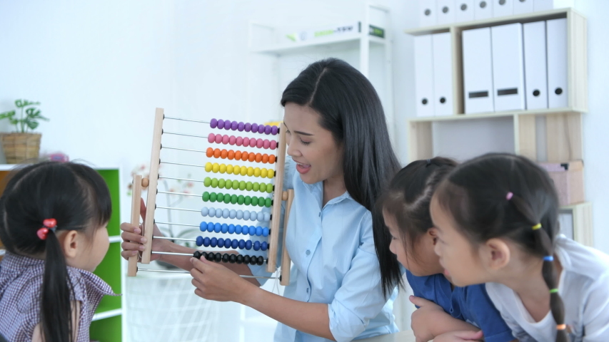 Educational concepts. The teacher is teaching math with abacus for kindergarten children in the classroom, With a bright smiley face. Royalty-Free Stock Footage #1047924148
