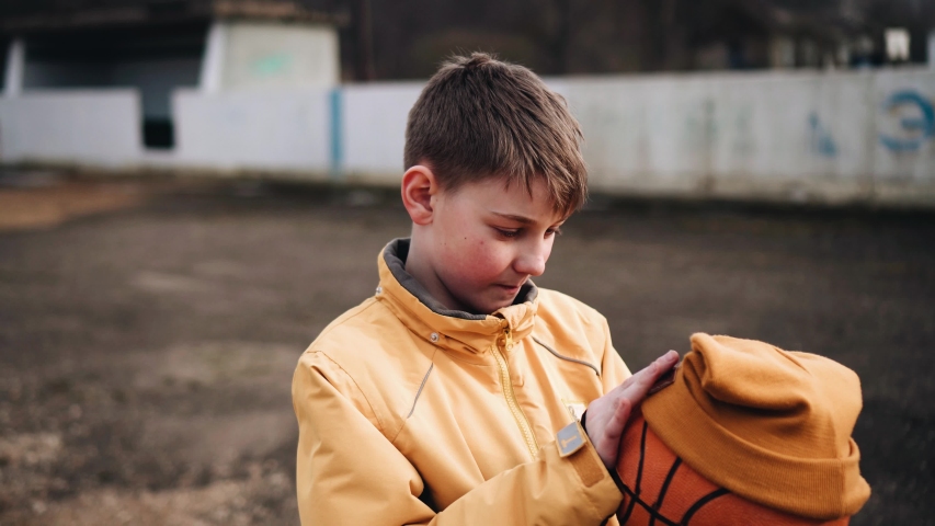 The boy puts his cap on the ball and examines it. Hilarious footage. The boy shows the ball to the camera. Cheerful child