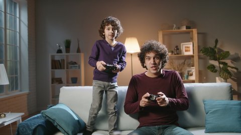 Funny south asian siblings are relaxing together, playing video games in front of tv, father and son expressing emotions while enjoying their hobby - family time concept 4k footage