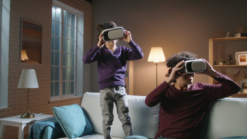 Authentic south asian siblings are having an experience in virtual reality, enjoying their together time at home in the evening - modern technologies, family time concept 4k footage
