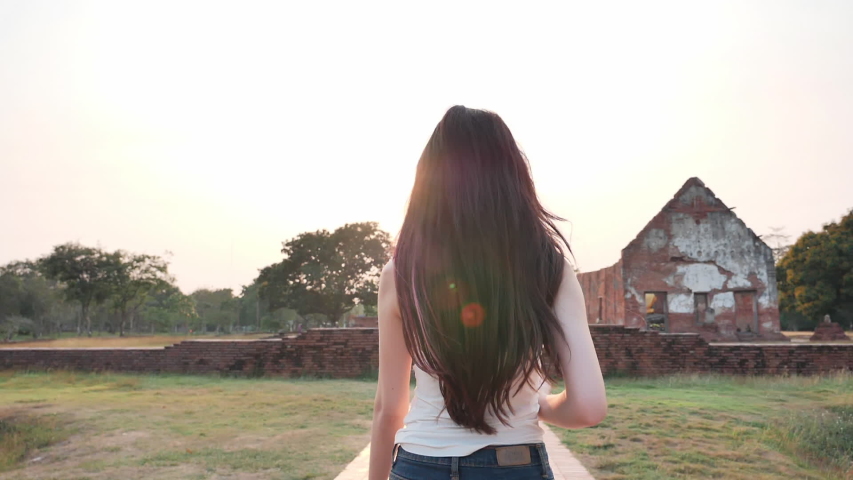 Rear view Young Asian women relaxation running and taking photos in world heritage city Ayutthaya, Thailand In the evening. Concept Freedom woman having fun, traveling on holidays. Slow Motion