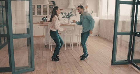 Beautiful couple dancing at home, Young man and woman cheerful  in kitchen. Loving people spending time together in their apartment. 4K slow motion