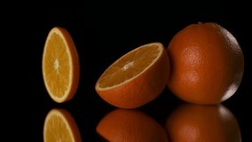A slice of ripe, juicy orange hovers in the air and quickly rotates in the black background.