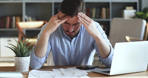 Depressed desperate man feeling worried about financial problem doing paperwork. Stressed businessman looking frustrated thinking of money debt, budget loss, bankruptcy sitting at home office desk.