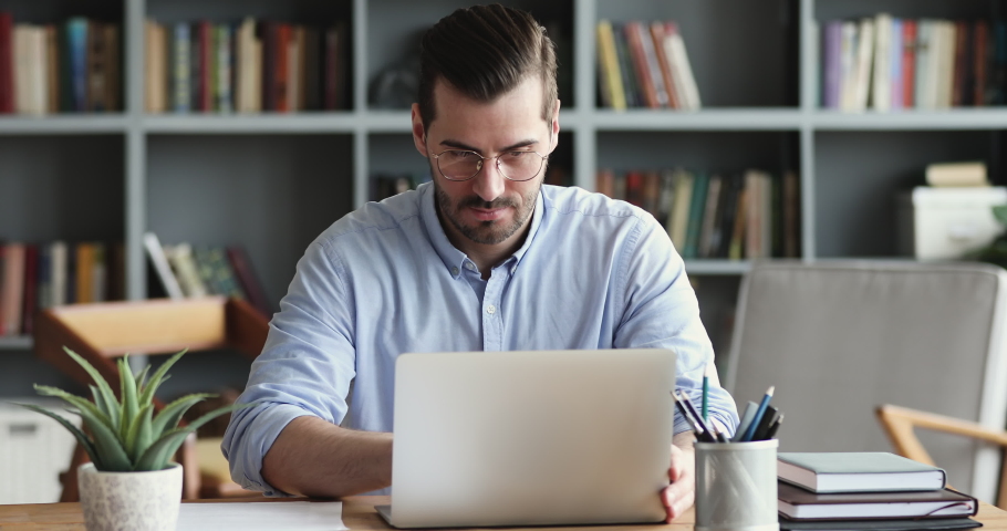 Focused business man entrepreneur typing on laptop doing research. Young male professional using computer sitting at home office desk. Busy worker freelancer working on modern tech notebook device. Royalty-Free Stock Footage #1047963103