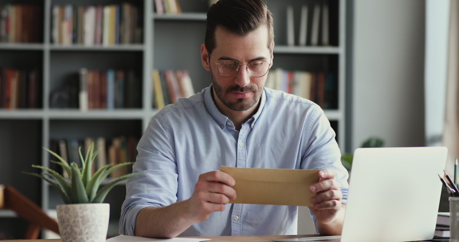 Excited male worker entrepreneur opening mail letter reading good news celebrating success. Happy businessman receiving loan approval, salary bonus, get promoted concept sitting at home office desk Royalty-Free Stock Footage #1047965533