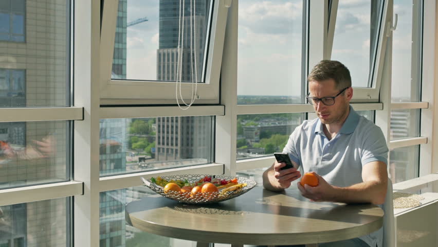 Man using cellphone and playing with an orange
