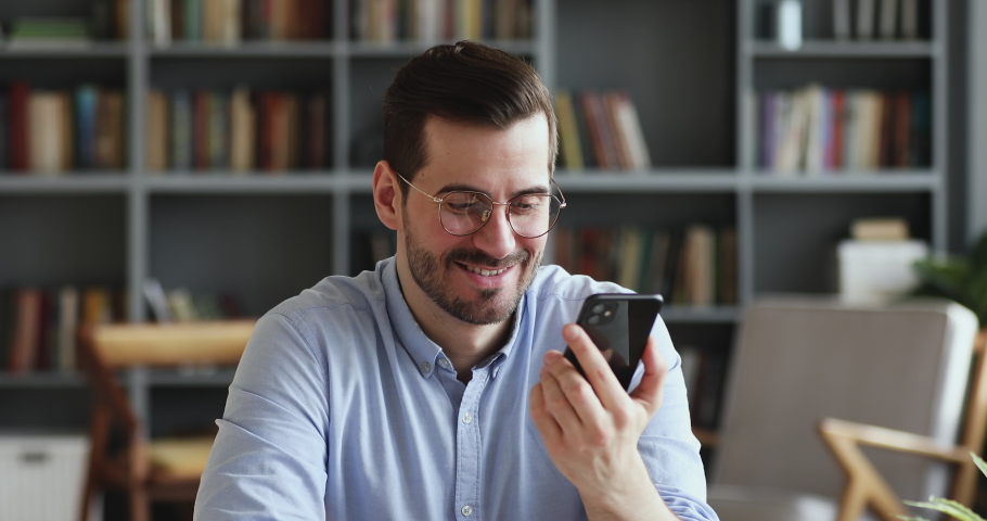 Smiling young man recording voice recognition message on speakerphone. Businessman using virtual assistant app sets reminder on smart phone at home office. Digital ai mobile assistance tech concept | Shutterstock HD Video #1047970870