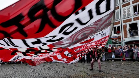 Düsseldorf, Germany - February 2020: Procession of Fortuna Düsseldorf fan club with man wave and flap big team's flag in parade of Carnival on Rose Monday.