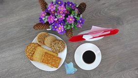 Top view spinning video of coffee cup with cookies and flowers. FHD.