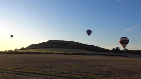 Warminster, Wiltshire / UK - September 14 2019: Hot air balloons flying at sunset in front of Cley Hill near Warminster in Wiltshire, England, United Kingdom