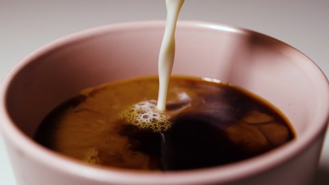Slow motion of pouring milk into coffee drink.