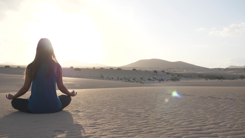 SLOW MOTION Yoga breathing and meditation pose. Panning shot of a young brunette woman shot from behind in the desert. | Shutterstock HD Video #1047982159