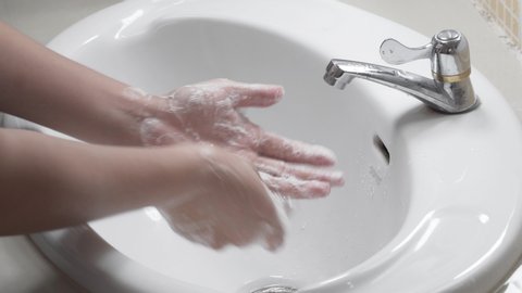 Close up of female lathering hands with soap before washing 
