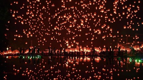 thousands of floating fire paper lanterns in the night sky with reflection in the pool at yee peng festival. Loy Krathong celebration, Chiangmai, Thailand