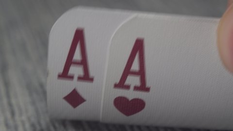Low angle closeup view of a male hand picking up and showing cards from a casino table