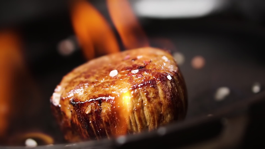 Filet mignon steak is fried in a pan with fire. Salt falls on a steak, slow motion. Royalty-Free Stock Footage #1047998908
