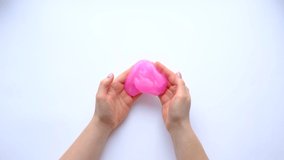 Woman hands playing with pink slime on white background. Trendy liquid toy. Top view. 4k footage.