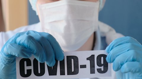 Doctor tearing a paper with the words "covid-19". The concept of defeating the coronavirus and developing vaccines and drugs