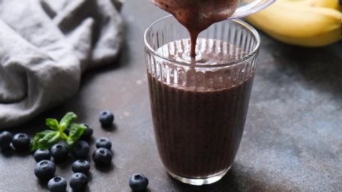 Pouring chocolate smoothie in glass slow motion closeup view. Healthy protein drink