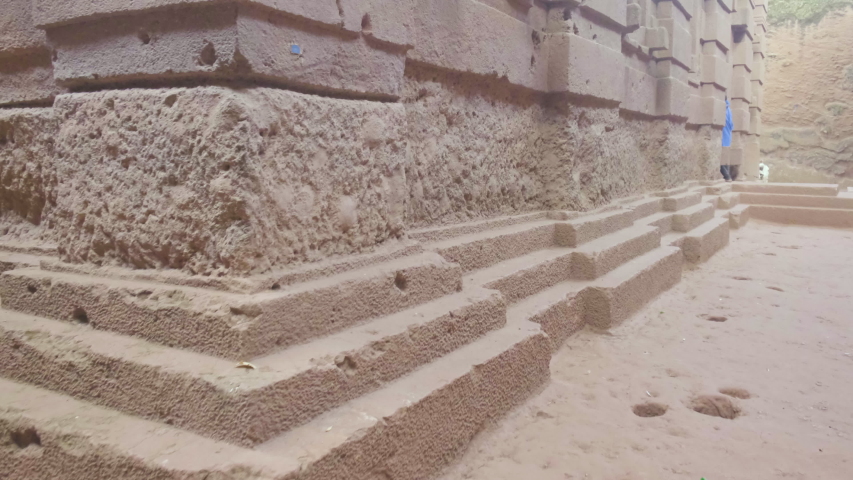 Camera forward push-in tilt up to reveal low angle view of side facade of Bet Amanuel rock-hewn church in Lalibela, Ethiopia