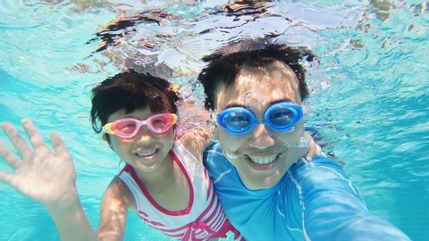 slow motion of asian cute daughter and father play and selfie happily in the swimming pool