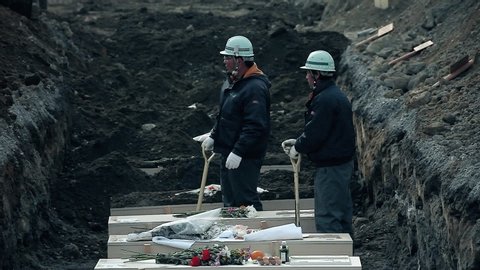 Fukushima, Japan - 03/11/2011 : burial of unknown japanese victims in white coffins after the tsunami. Japanese workers are close to the coffins to bury the dead.