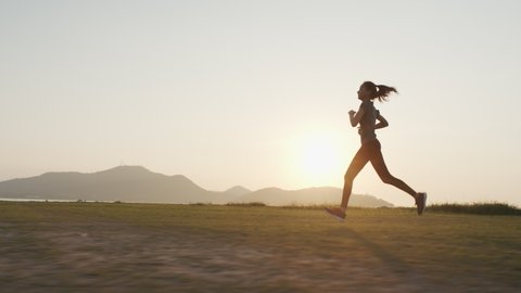 Young Asian women are exercising with outdoor running with a mountain background. When the sun sets in Thailand in summer, Concept healthy running and outdoor exercise,Tracking dolly shot Video Stok