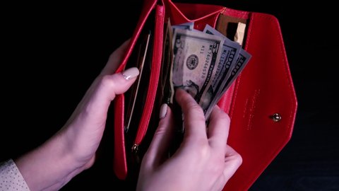 The girl opens the red wallet and counts the money, then closes it. Earnings in the United States. Minimum cash allowance. Point of view shot.