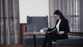 Businesswoman holding papers and drinking coffee in restaurant lobby
