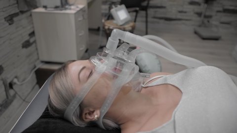 Girl lies on bed with artificial respiration mask