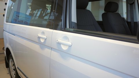 A male hand opens the door of a new white car at a car dealership. Before the test drive