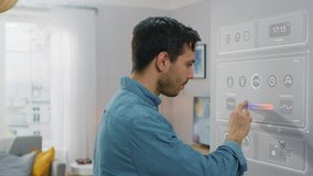Handsome Young Man Interacts with an Augmented Reality Software. He is Setting Climate Control Unit to a Higher Temperature. Smart Home Concept with Transparent Screen Made with VFX Special Effects. - Powered by Shutterstock - Get 15% off with code: PIKWIZARD15
