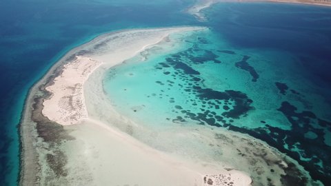 High angle drone flight of small strip of sand connecting two unspoiled islands in the Red Sea, natural landscapes and scenery in Saudi Arabia
