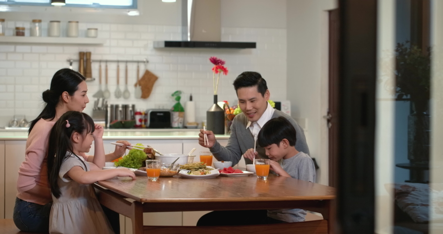 Happy family enjoy breakfast together. Cheerful young asian parents and cute small kids enjoy breakfast together on dining table at home. wonderful moment family concept 4k footage. Royalty-Free Stock Footage #1048063186