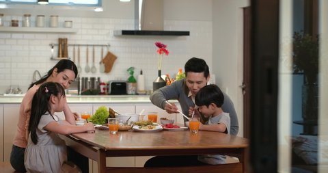 Happy family enjoy breakfast together. Cheerful young asian parents and cute small kids enjoy breakfast together on dining table at home. wonderful moment family concept 4k footage.
