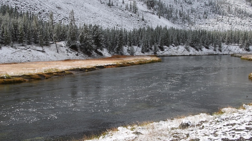The Madison River with a light dusting of snow, Yellowstone National Park. Wyoming. Camera panning left to right, tilting up.