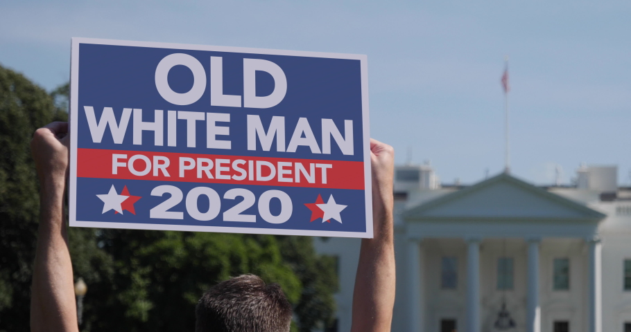 A man holds a Old White Man for President 2020 election protest sign in front of the White House on a sunny summer day.  	