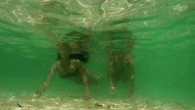Beauty young female swimming underwater. Underwater view happy diving teen girl with long hair smiling and waving at camera. Slow motion video footage