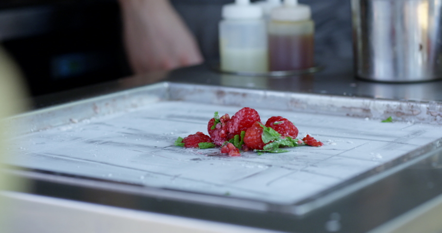 Cream being poured on raspberries on cold plate - boutique ice cream - extreme close up