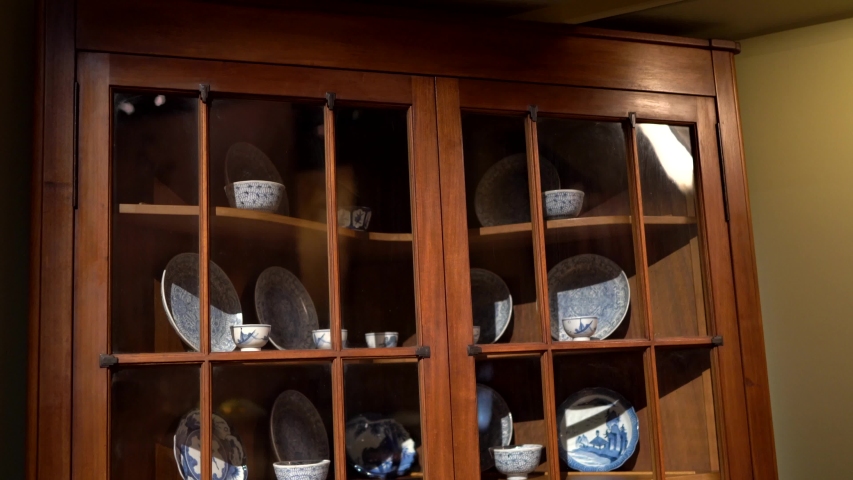 This tilting video shows a wooden china cabinet full of antique china dishes and pieces.