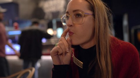 This video shows caucasian woman wearing glasses and eating steak with a fork at a restaurant.
