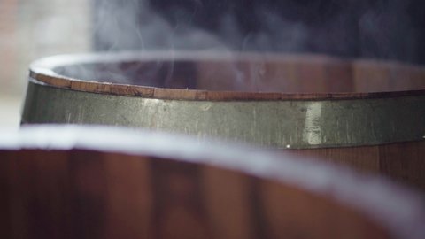 Steaming wooden barrel after charring with side lighting, slow motion close up