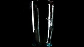 Water pouring into transparent glass isolated on black background in slow motion. Healthy lifestyle concept.