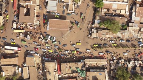 The drone flies up with a topdown view towards the right upon the length of a very busy and crowded but colourfull city street in Mali Aerial Drone Footage 4K