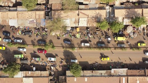 The drone flies up with a topdown view upon the length of a very busy and crowded but colourfull city street in Mali Aerial Drone Footage 4K