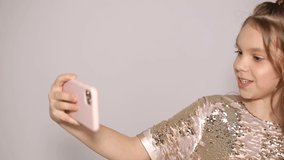 Portrait of girl holding smart phone in hand taking selfie on front camera isolated on white background, schoolgirl enjoys weekend break