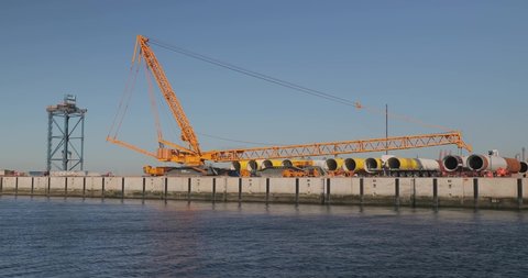 ROTTERDAM, THE NETHERLANDS - CIRCA 2019: Storage and loading site for elements of wind turbines to be assembled for huge off-shore wind farms under construction on the North Sea. Huge metal tubes.
