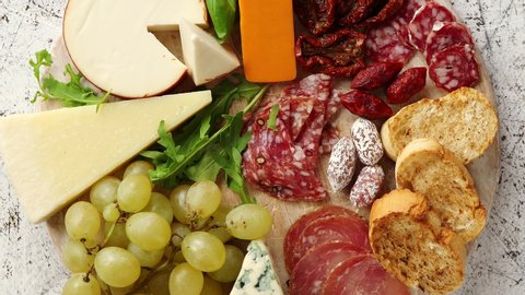 Assortment of spanish tapas or italian antipasti with meat, ham, olives, cheese, nuts and bread placed on a white rusty table. Top view flat lay with copy space background