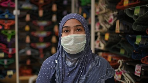 young beautiful Muslim woman in medical mask,looking at camera.Health care and medical concept.
